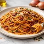 Caramelized shallot pasta with glossy sauce and Parmesan twirled on a fork