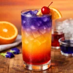 desert sun mocktail layered drink with orange juice grenadine and butterfly pea tea creating sunset colors