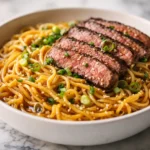 Garlic butter steak lightning noodles in a white bowl with juicy medium-rare steak slices and glossy sauce