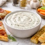 creamy mazzios ranch recipe copycat dressing in a bowl with pizza slices and breadsticks on white marble background