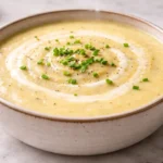 Creamy potato leek soup in a bowl with chives and cream swirl