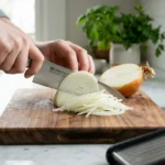 Julienned onion strips on a wooden cutting board with a chef's knife and fresh parsley Title : How to Julienne an Onion