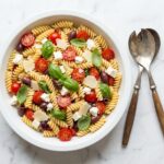ina garten pasta salad recipe with tomatoes feta basil and olives on white marble