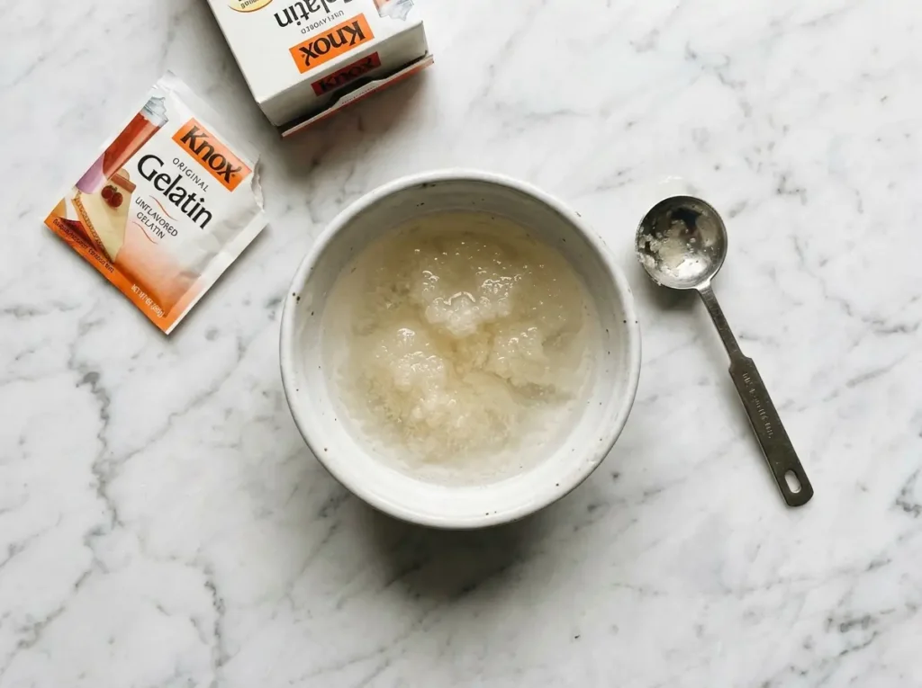Knox gelatin granules blooming in cold water in a white bowl