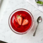 Easy strawberry gelatin dessert in a glass bowl garnished with fresh strawberries73 chars