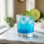 Blue lotus drink in a glass with lime on marble counter