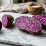purple sweet potato sliced open showing vivid purple flesh on marble