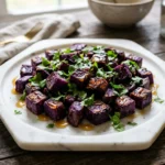 roasted purple sweet potato cubes with honey lime drizzle on marble plate